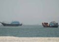 Cargo ships sailing through the Strait of Hormuz amid heightened regional security and naval monitoring