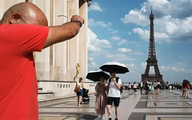 People walking in Paris under intense sunlight during a severe Europe heatwave