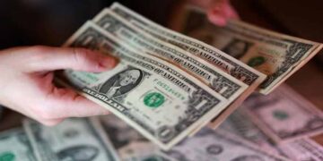 US dollar banknotes displayed alongside financial market charts reflecting changing Federal Reserve interest rate expectations.
