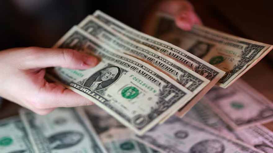 US dollar banknotes displayed alongside financial market charts reflecting changing Federal Reserve interest rate expectations.