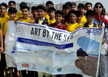 Students collecting litter and discarded seashells during a beach cleanup drive at Seaview, Karachi.